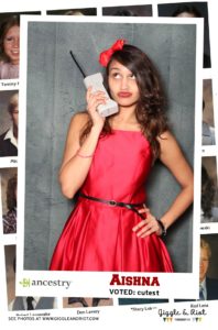 woman poses for photobooth with phone prop and red dress