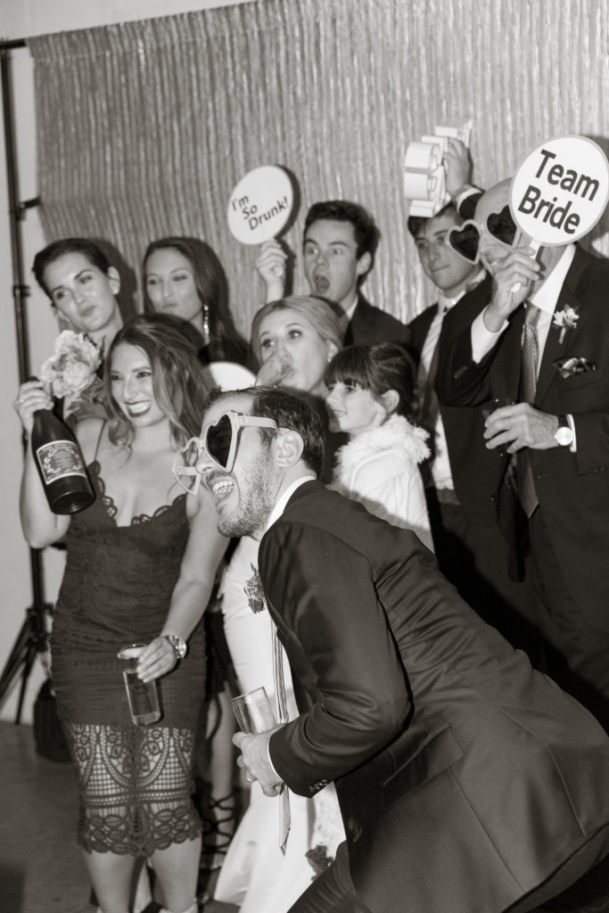 a group of people pose for a photo booth with props 