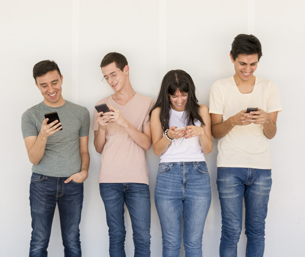 4 people look and smile at their cell phones