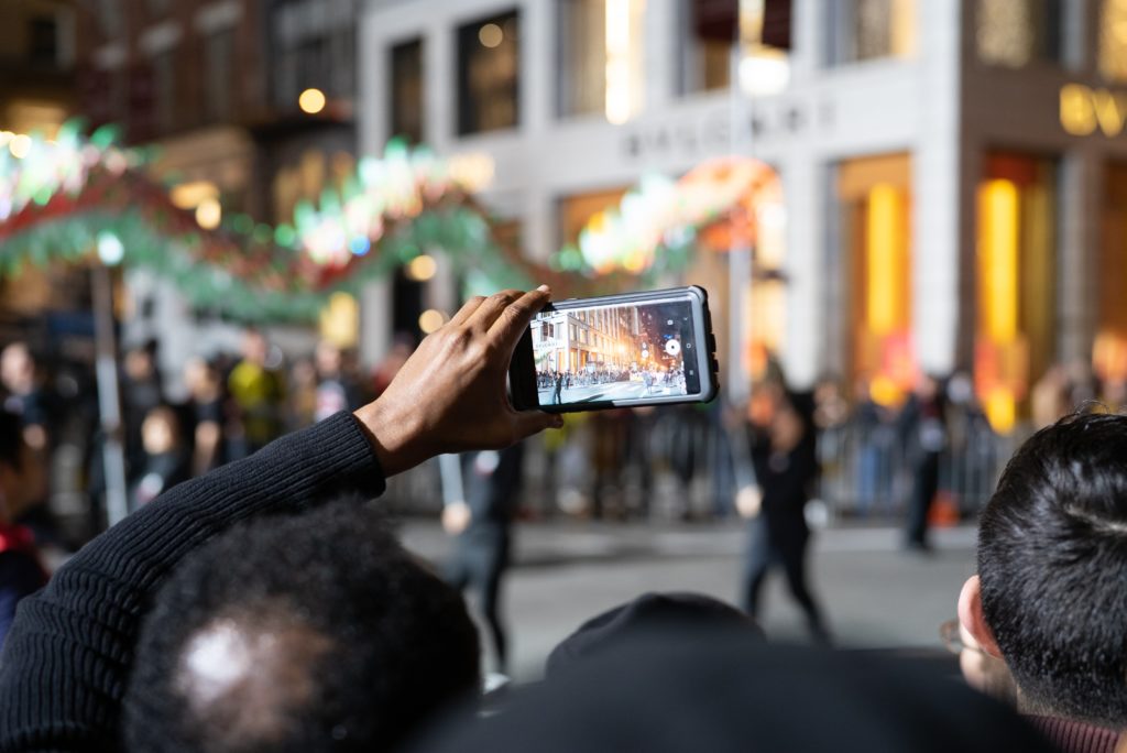 People hold up a smartphone and take a video of the street at night