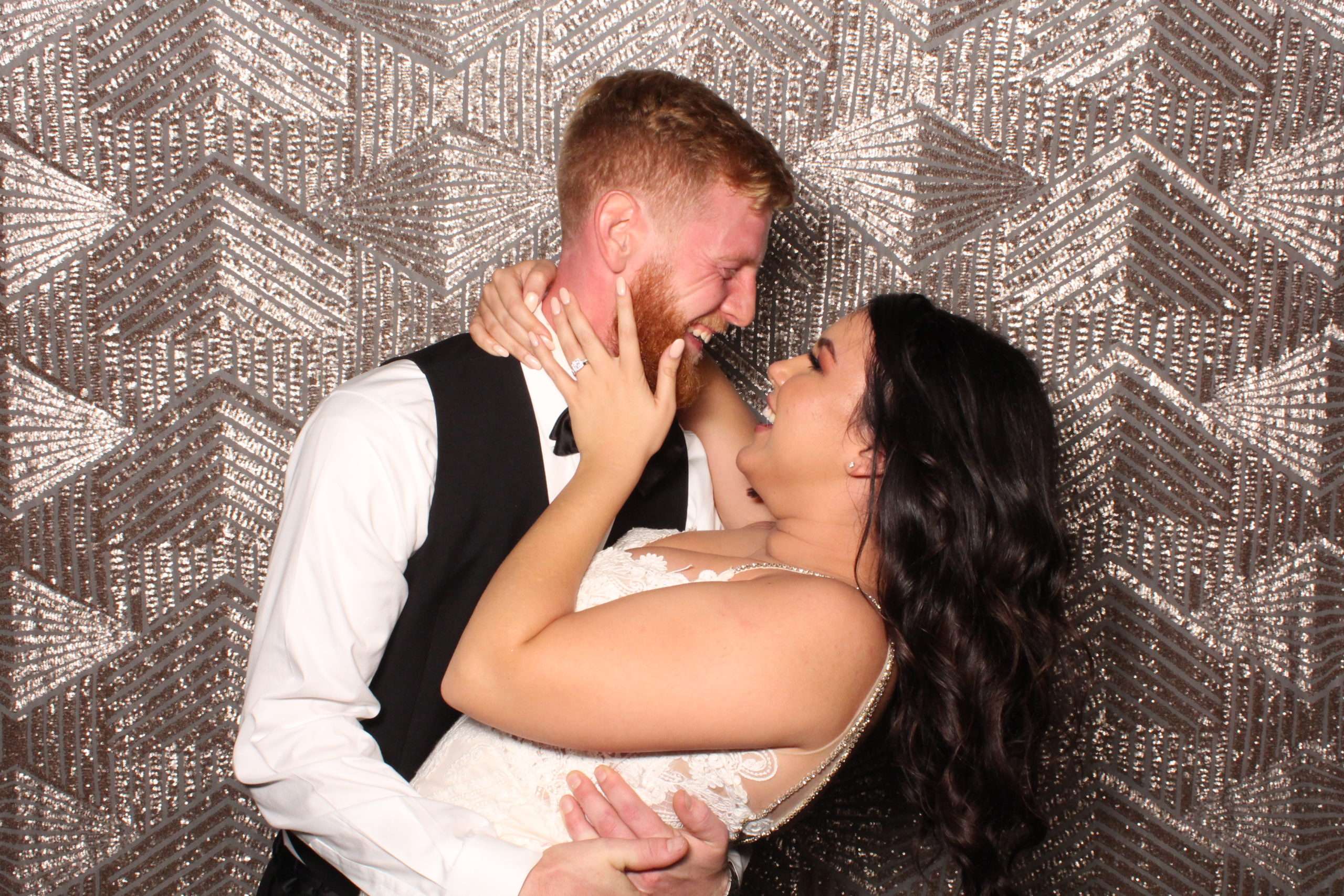 bride and groom hold eachother and laugh in photobooth