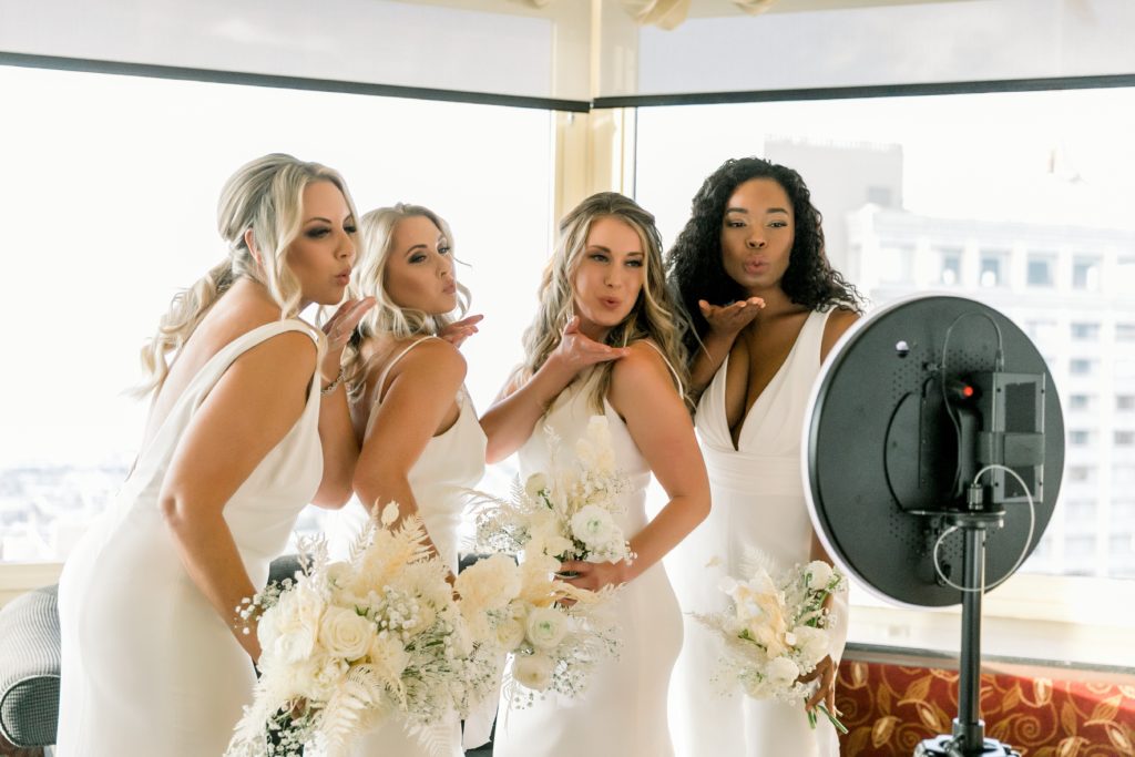 4 bride models pose and blow kisses to traveling photobooth