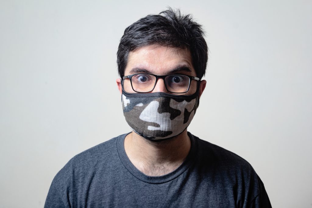 man in mask and glasses smiles for camera