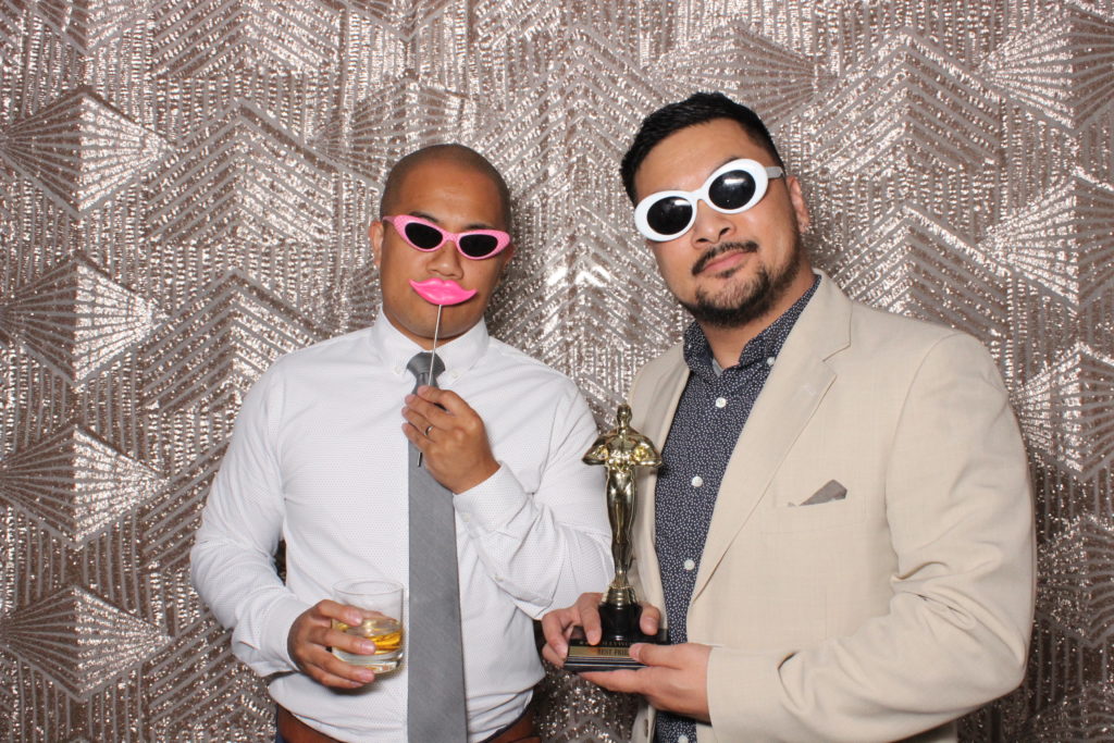 two men pose with props in wedding photobooth