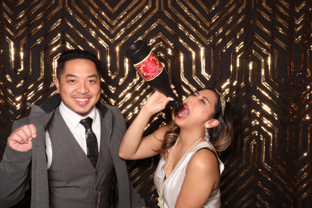 man and woman pose with props in wedding photobooth