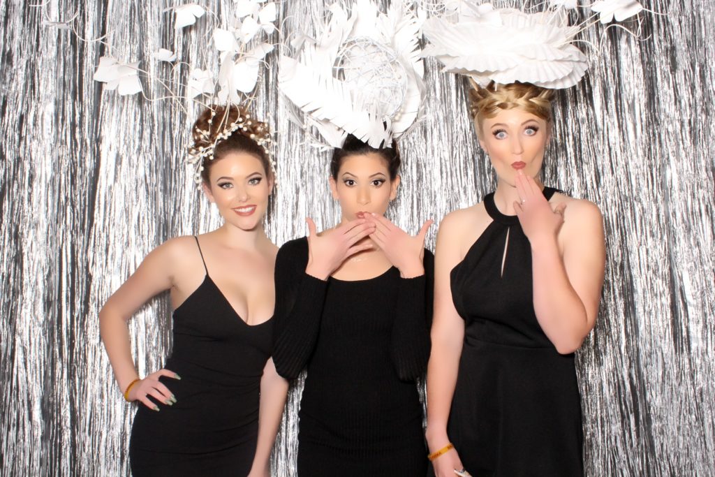 four event performers pose in beauty booth with tinsel backdrop and head dresses