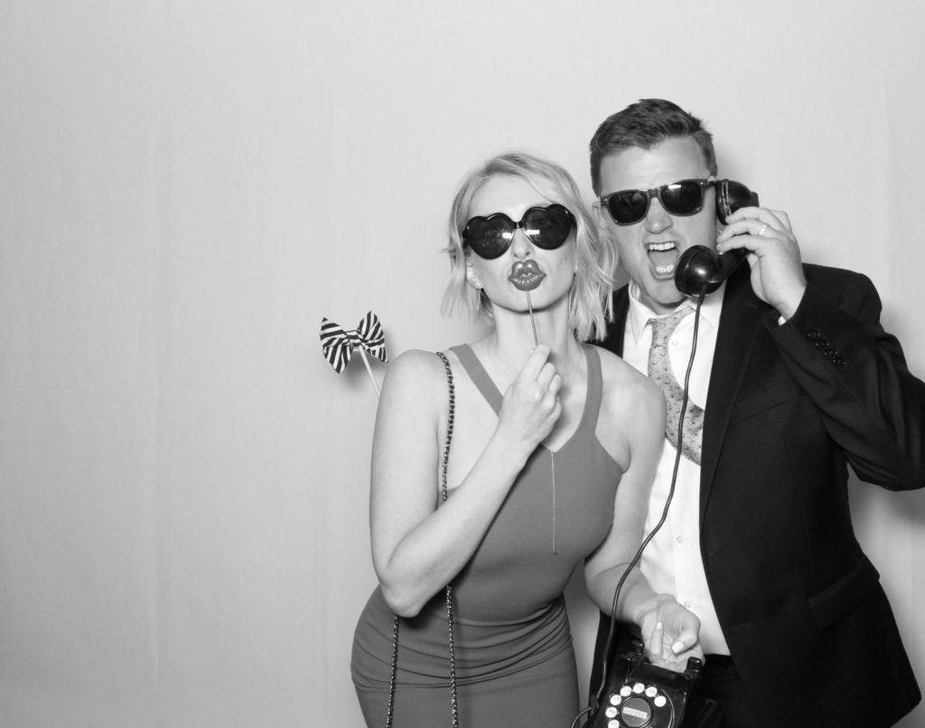 man and woman pose for photobooth in black and white picture with props