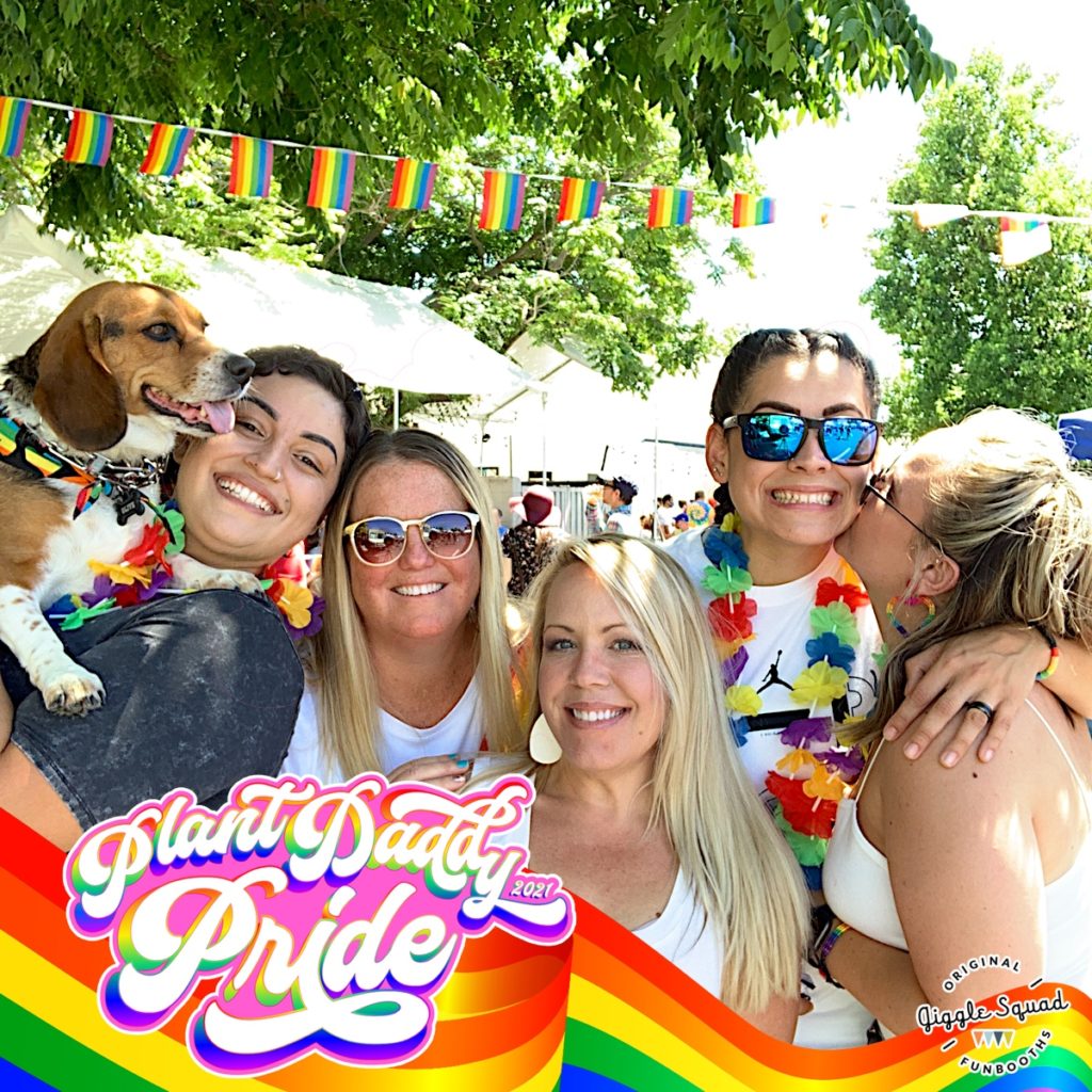 five women and a dog pose for photobooth with rainbow frame