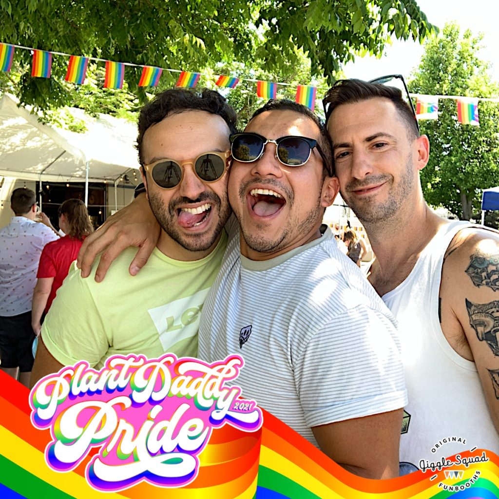 four men pose for photobooth with rainbow frame
