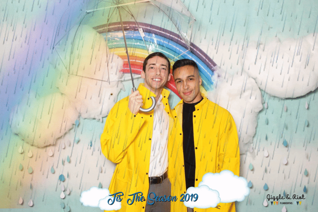 two men in rain coats pose in custom rainfall backdrop